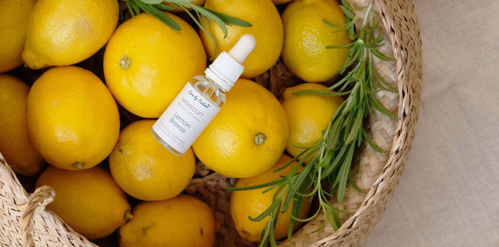Lemon Breeze vaskeduft fra Care by Nature der ligger i en flettet kurv med friske citroner og et bundt rosmarin