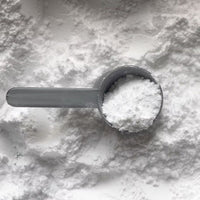 hvidt natriumbikarbonat med fyldt måleske ovenpå set fra oven