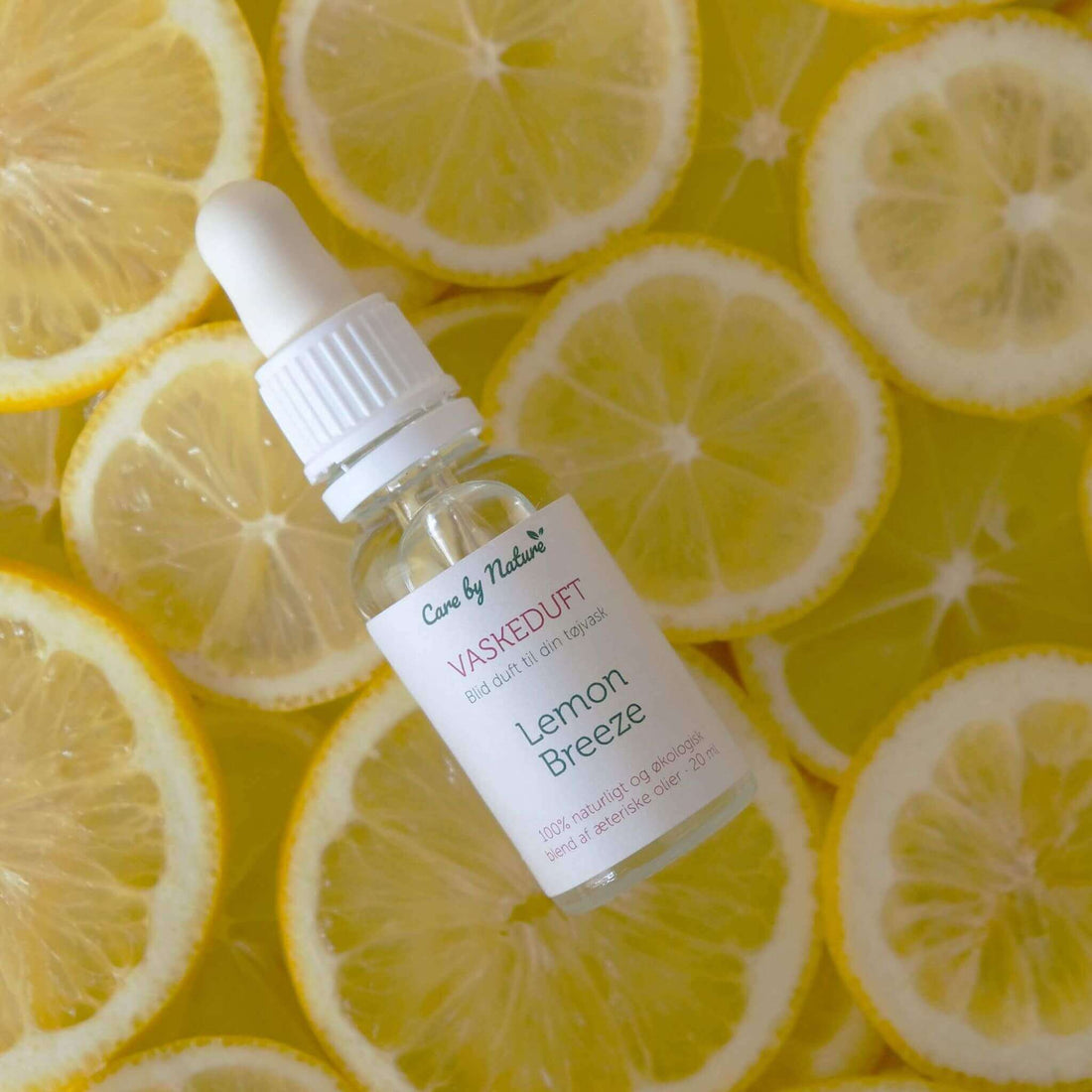 care by nature vaskeduft lemon breeze i klar glasflaske ovenpå skiver af citroner