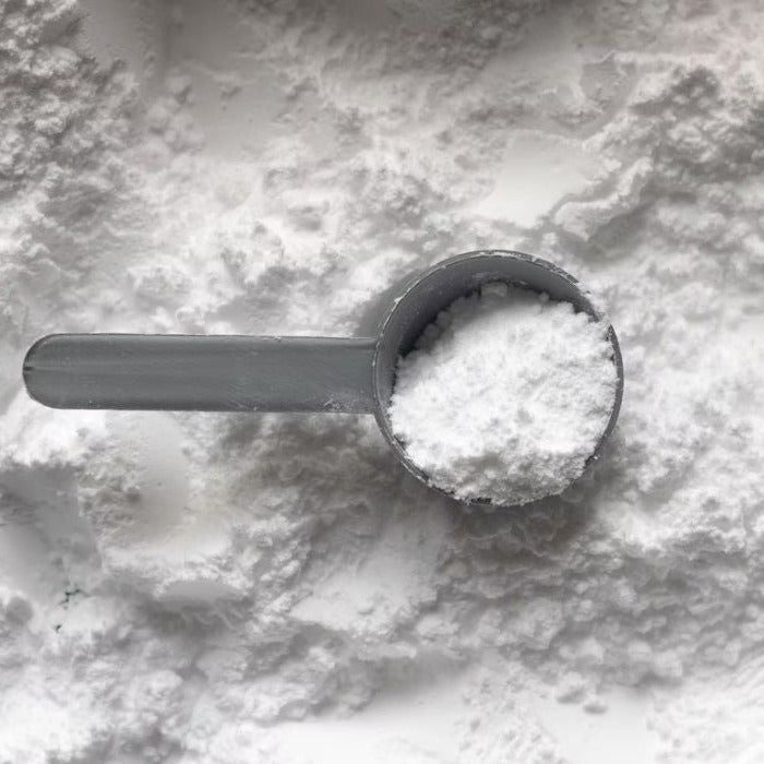 hvidt natriumbikarbonat med fyldt måleske ovenpå set fra oven