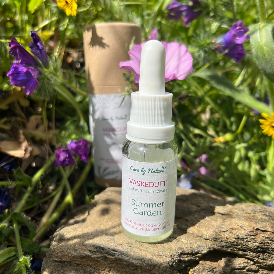 Vaskeduften Summergarden stående på en sten i mellem sommerblomster
